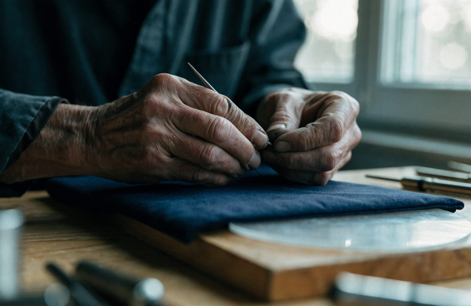 Hände eines erfahrenen Handwerkers an der Werkbank Hände eines älteren Handwerkers bei feiner Arbeit an einer Werkbank – KI-generiertes Symbolbild