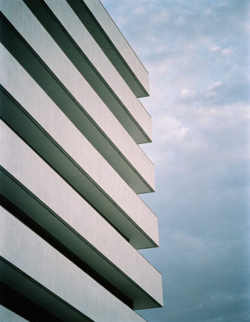 Gestaffelte Geschosse eines Bürogebäudes Übereinander gestaffelte Geschosse eines hellen Bürogebäudes vor dem Himmel – KI-generiertes Symbolbild