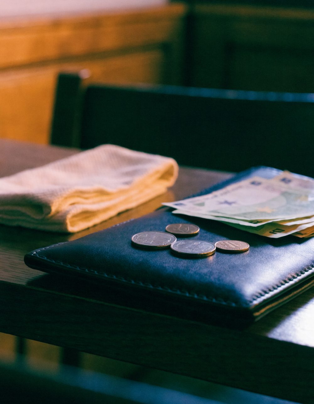 Trinkgeld auf einer Rechnungsmappe Münzen und Geldscheine auf einer dunklen Rechnungsmappe neben einer Serviette – KI-generiertes Symbolbild